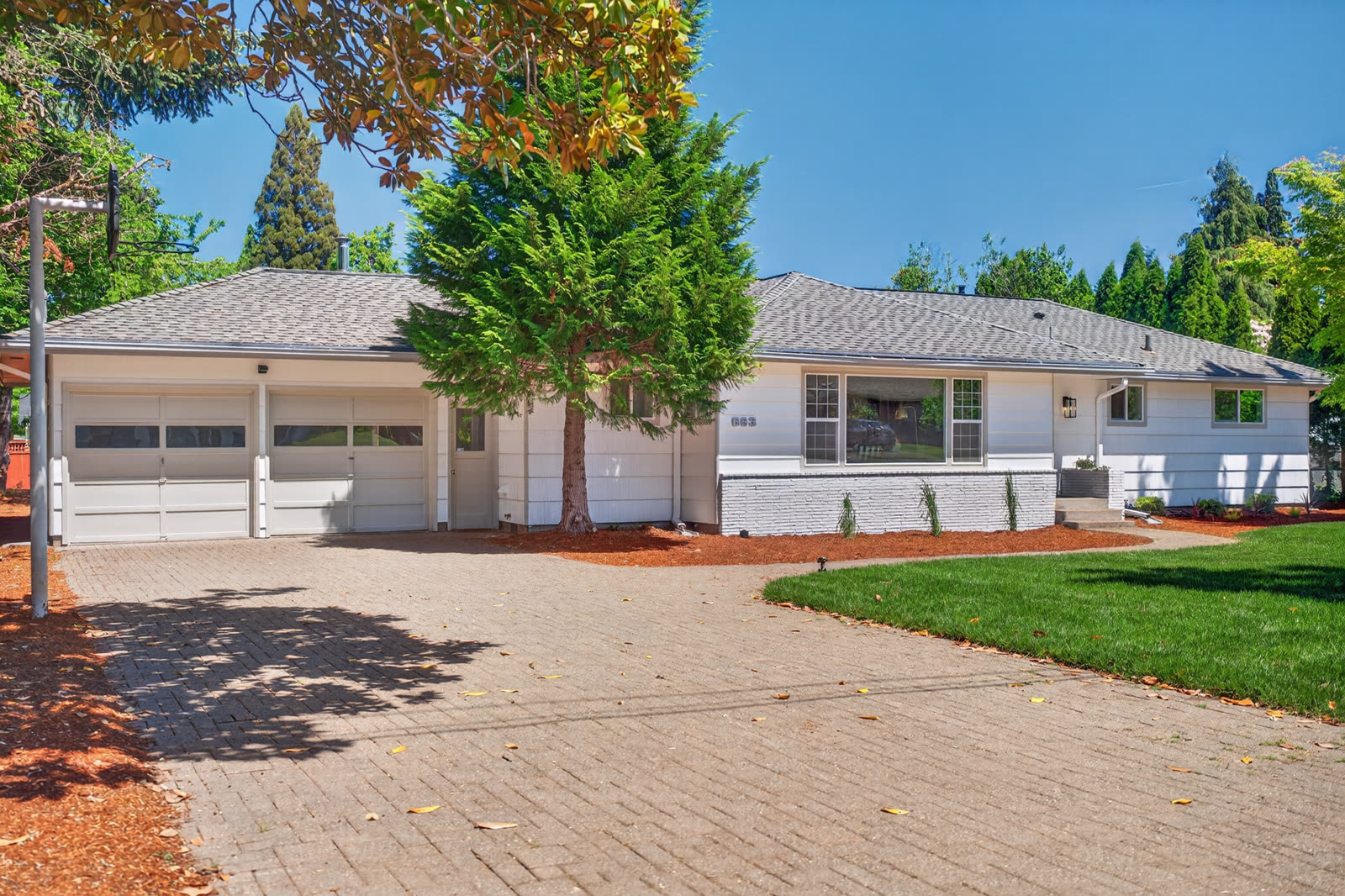 Renovated white ranch home with painted brick, new landscaping, and paver driveway