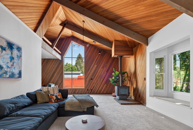 Vaulted living room with cedar plank ceiling and wood stove after renovation